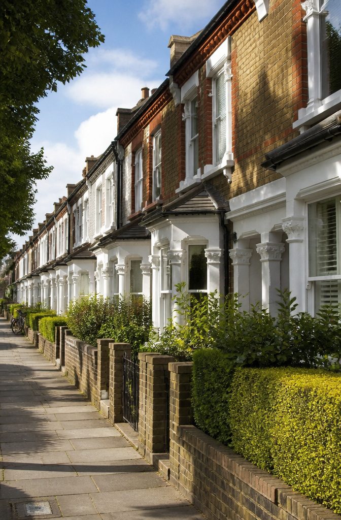 A row of terrace houses with manicured front gardens and inviting façades.